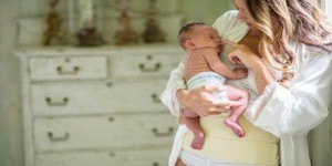 A mother holding her newborn while wearing the AbdoMend cotton support band